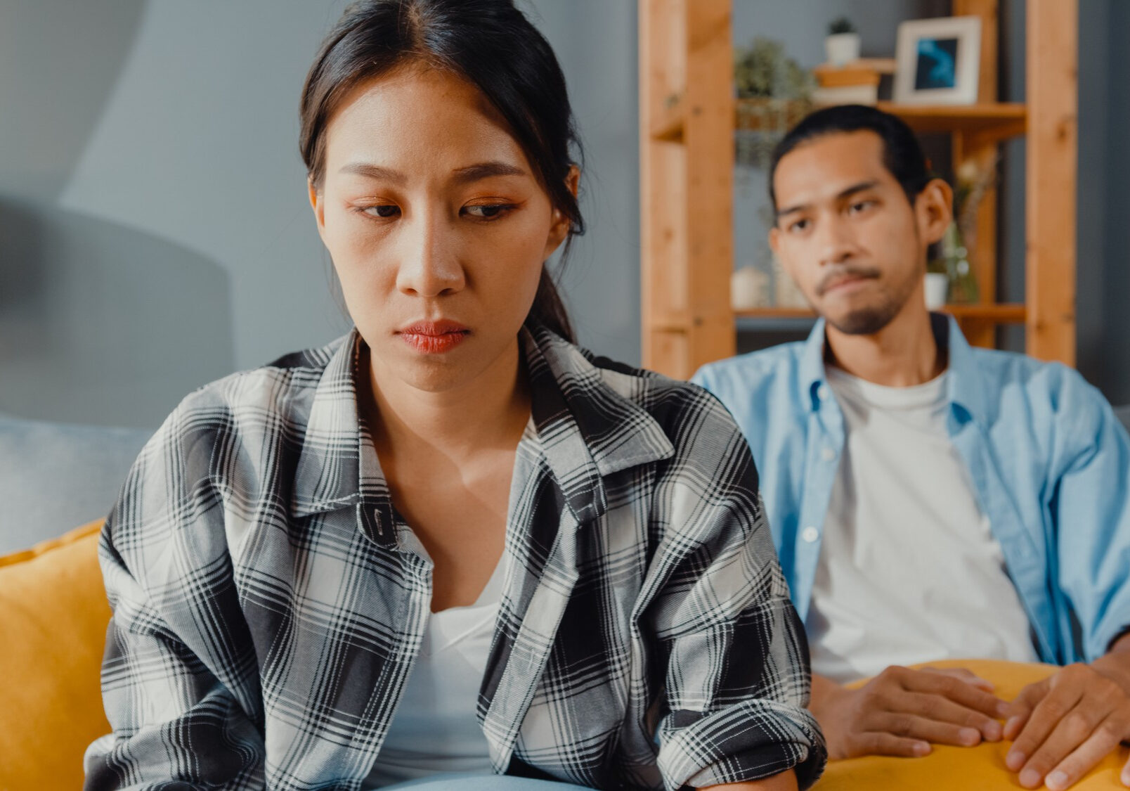 upset-asian-couple-sit-couch-living-room upset-asian-couple-sit-couch-living-room